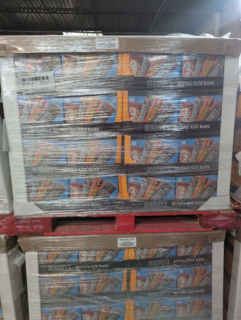 Wrapped pallets of Hershey's variety bars with date labels, part of excess candy inventory
